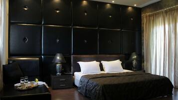 A modern bedroom with a large bed, two bedside tables with lamps, and a dark headboard.