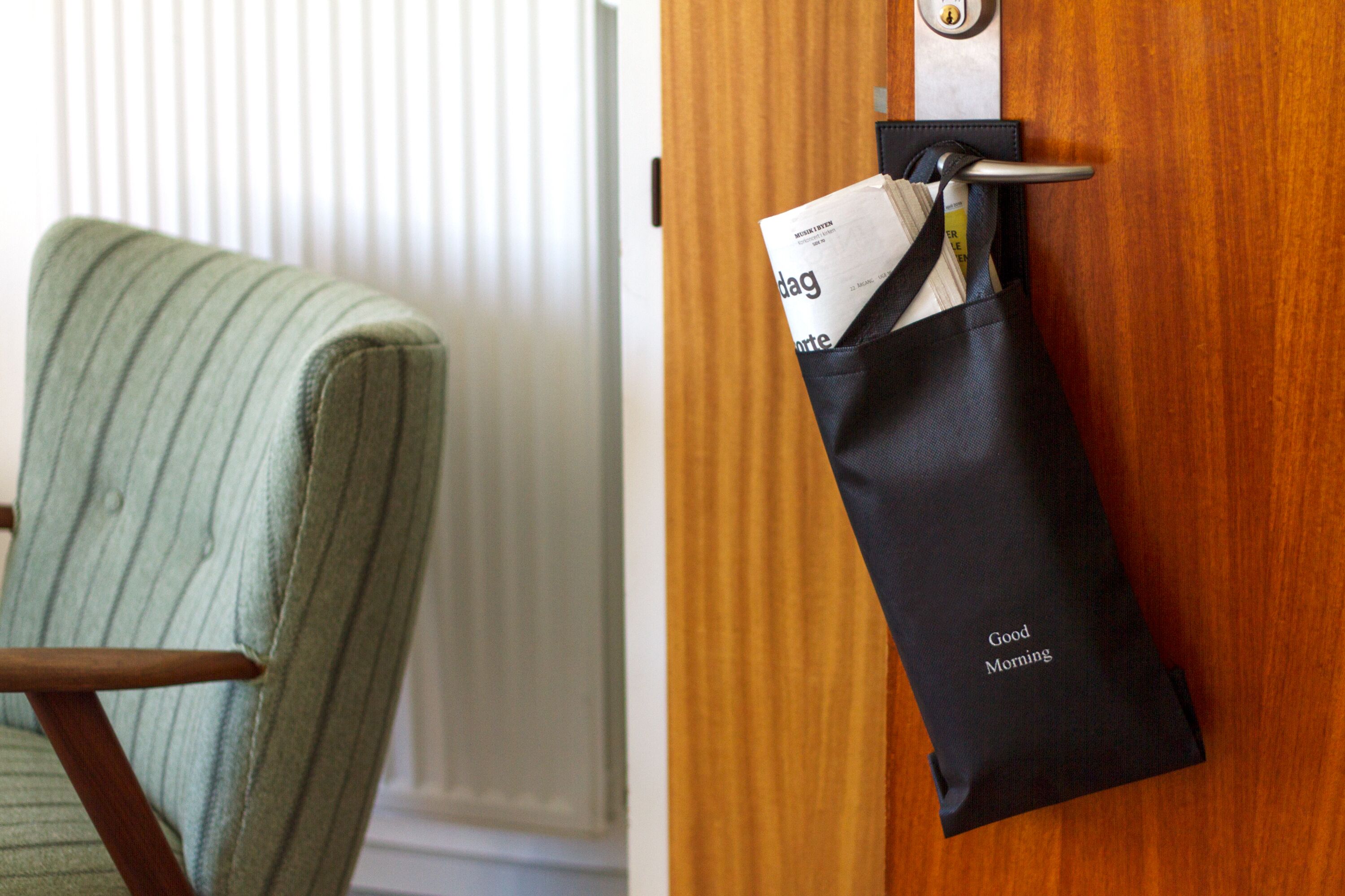 A wooden door with a black bag hanging on a hook labeled "Good Morning".