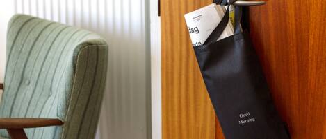 A wooden door with a black bag hanging on a hook labeled "Good Morning".