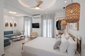 Une chambre d’hôtel moderne équipée d’un grand lit, d’un canapé, d’une télévision et d’un ventilateur de plafond.