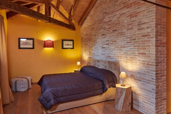 Un dormitorio con una cama de madera, una pared de ladrillo y dos cuadros enmarcados.