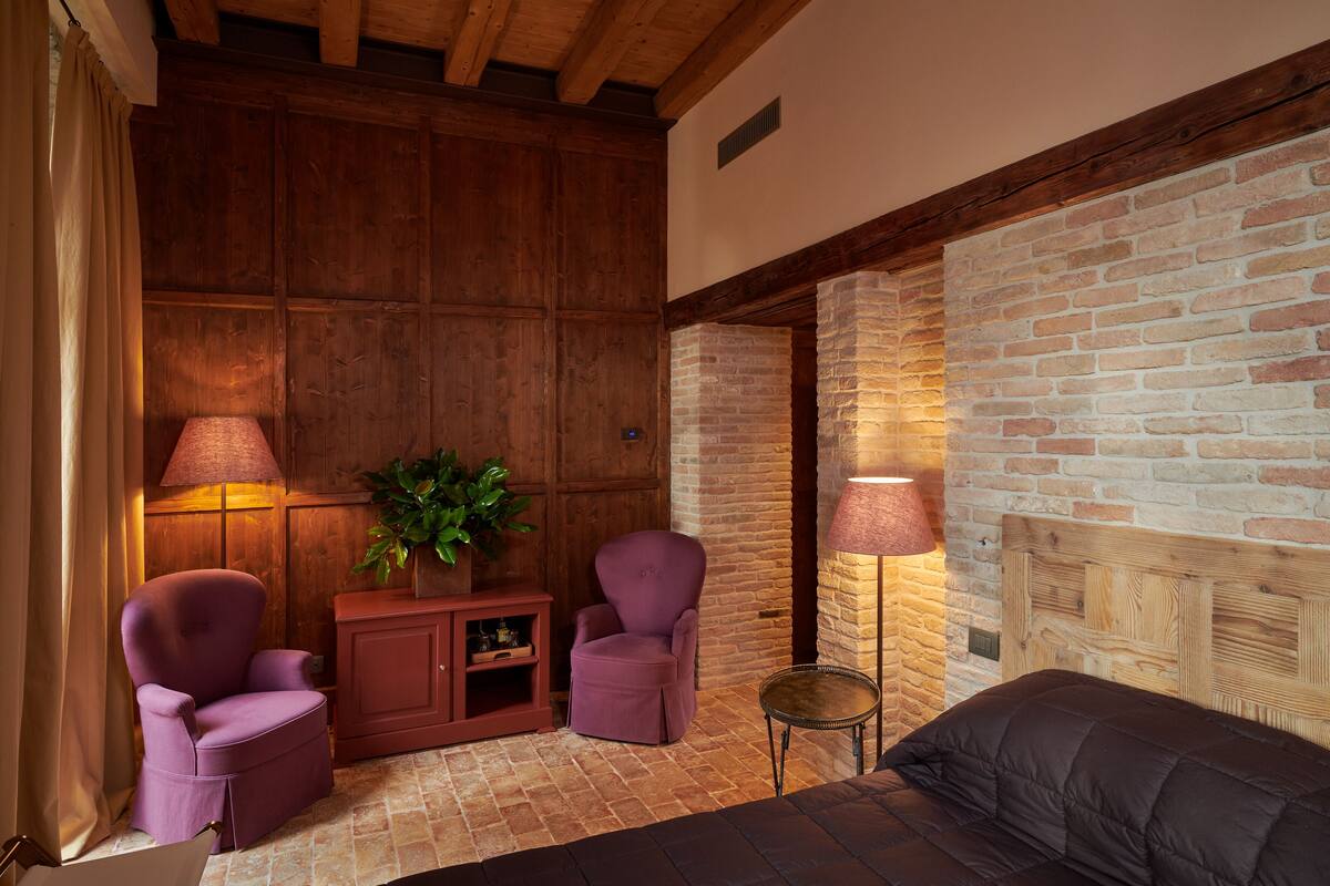 Una habitación acogedora con una cama, dos sillones, una mesita y una planta en maceta.