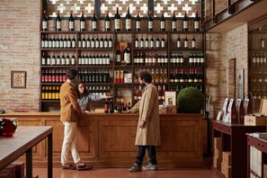 A bar area with wooden shelves stocked with wine bottles, a counter, and a brick wall. - Castello di Roncade (Roncade)
