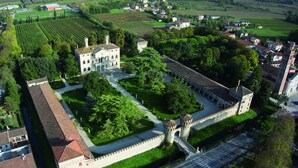 Vista aérea de un castillo histórico con muralla fortificada, patio central y vegetación circundante.