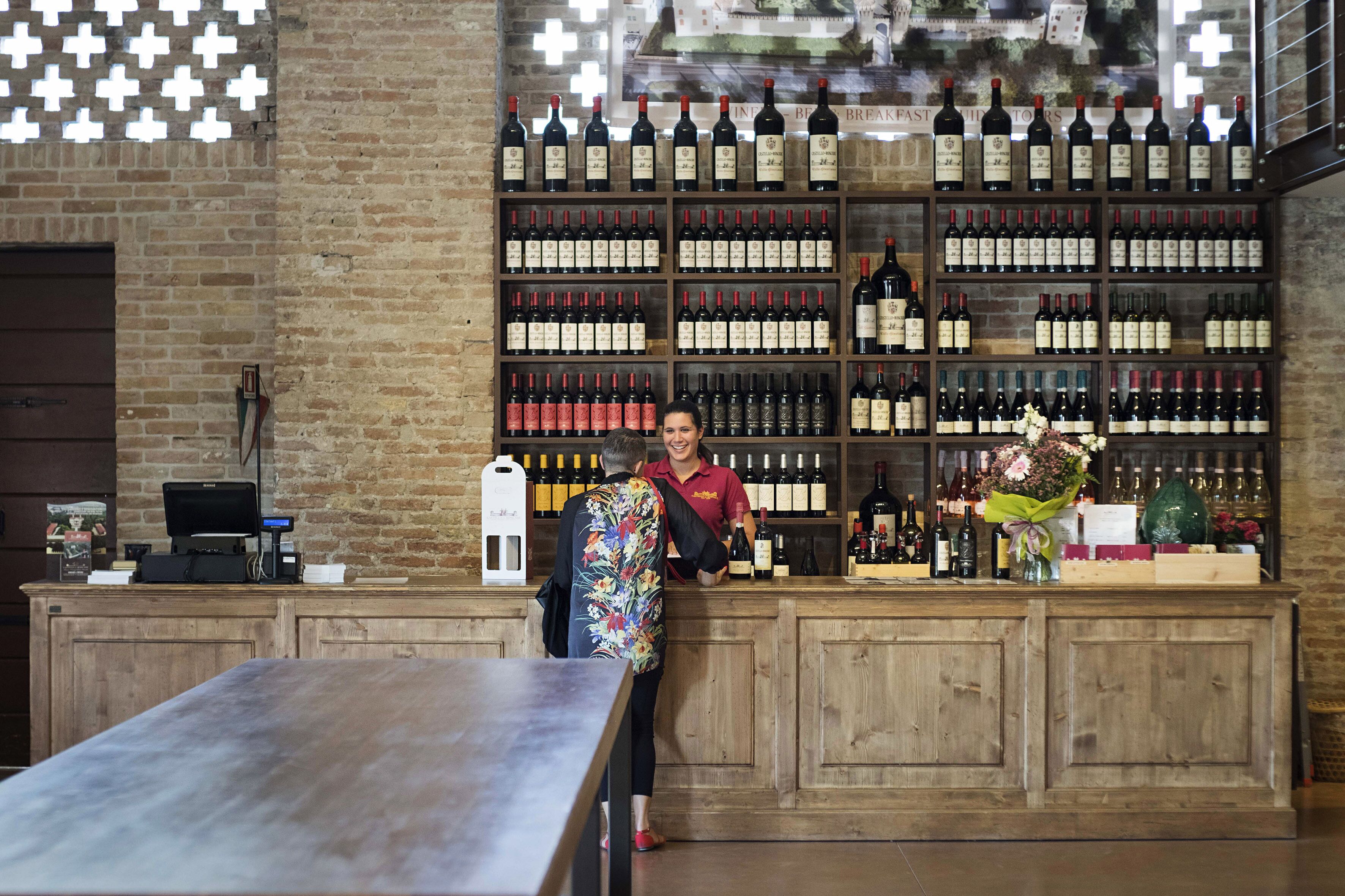 Una zona de bar con mostrador de madera, exhibición de vinos y caja registradora.