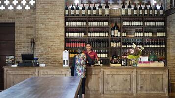 Una zona de bar con mostrador de madera, exhibición de vinos y caja registradora.