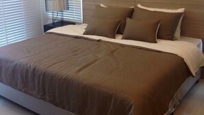 A modern bedroom with a large bed, a nightstand, and a lamp. - Baan Sarinya Pool Villa (Cha-am)
