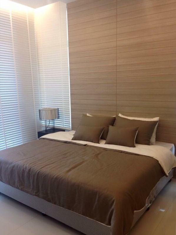 Un dormitorio moderno con una cama grande, una mesita de noche y una lámpara.