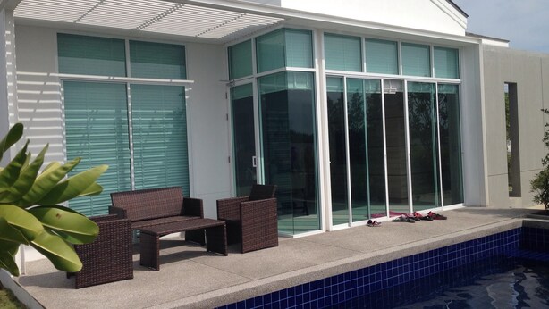 A modern house with a swimming pool, large glass windows, and outdoor seating. - Baan Sarinya Pool Villa (Cha-am)