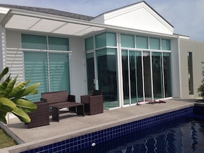 A modern house with a swimming pool, large glass windows, and outdoor seating.