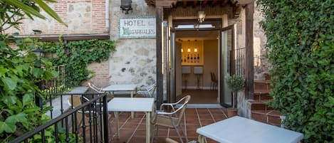 Un patio con asientos al aire libre, un cartel que indica Hotel Lo Cigarrales y una escalera que lleva a la entrada.