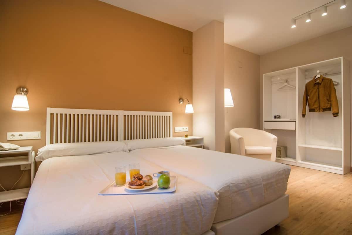 Una habitación de hotel con una cama grande, mesitas de noche, un armario y una zona de estar.