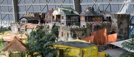 A model of a medieval village with thatched-roof structures, a yellow building, and a large stone wall.