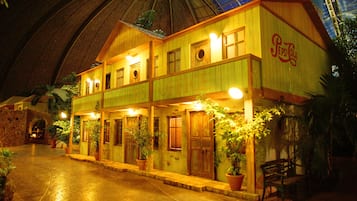 A building with a 'Pepsi Cola' sign, wooden exterior, multiple doors, and potted plants.