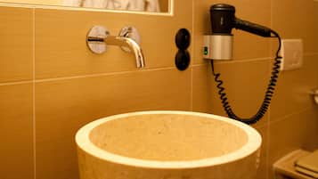 Ein Badezimmer mit Waschbecken, Fön und Spiegel.