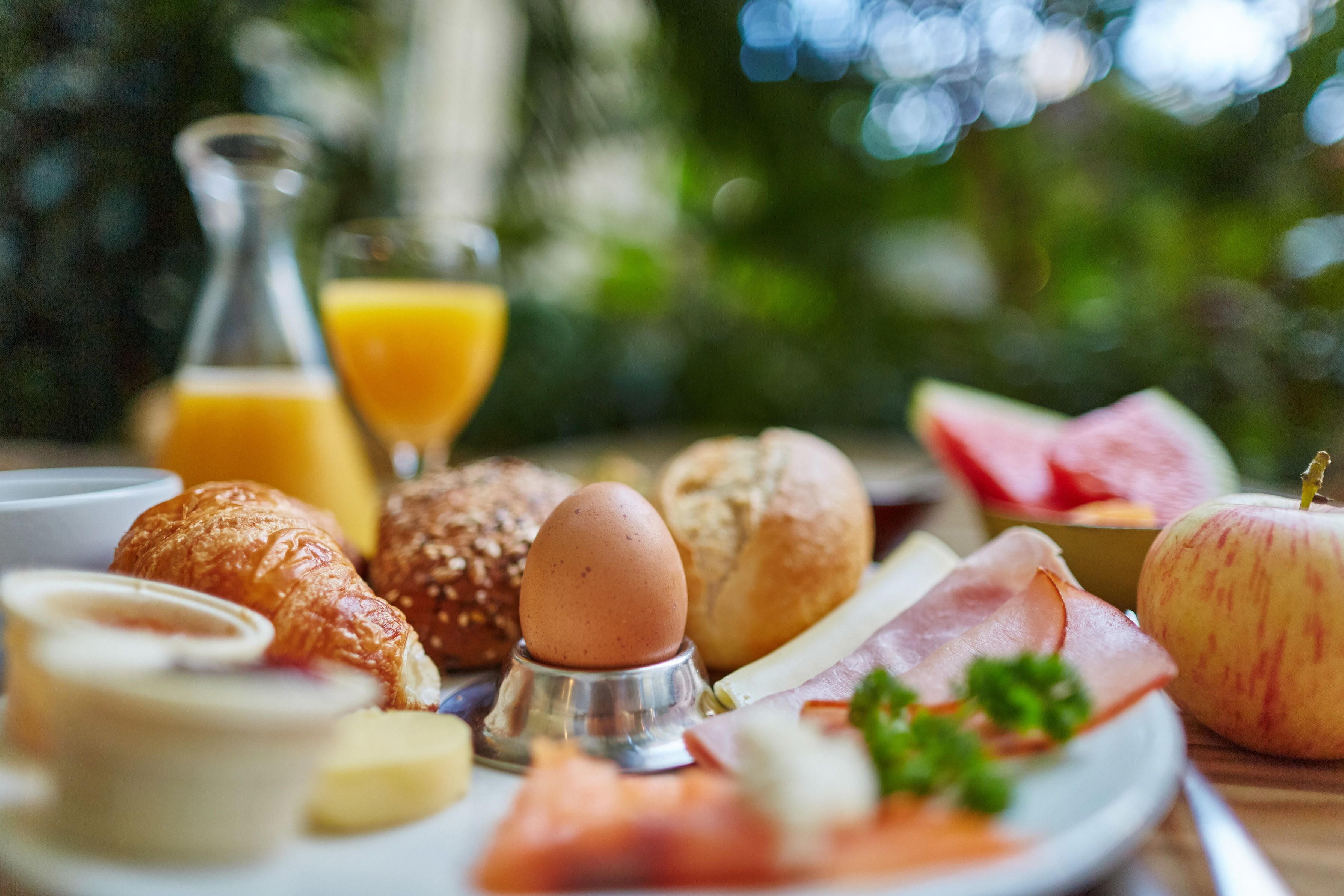 A breakfast spread with croissants, eggs, ham, cheese, and a glass of orange juice.