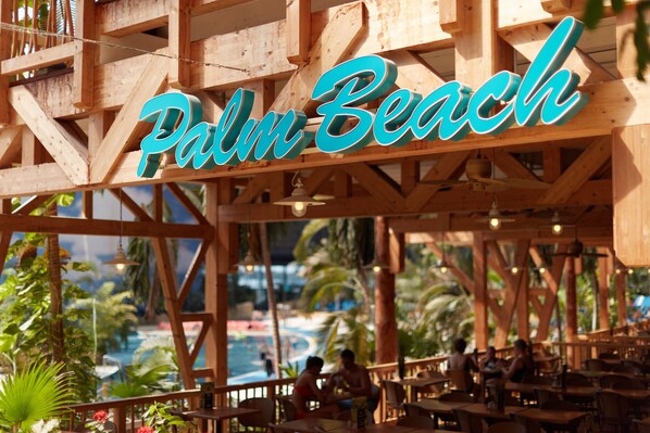 Une structure en bois portant l’inscription « Palm Beach », indiquant un complexe hôtelier ou un hôtel.