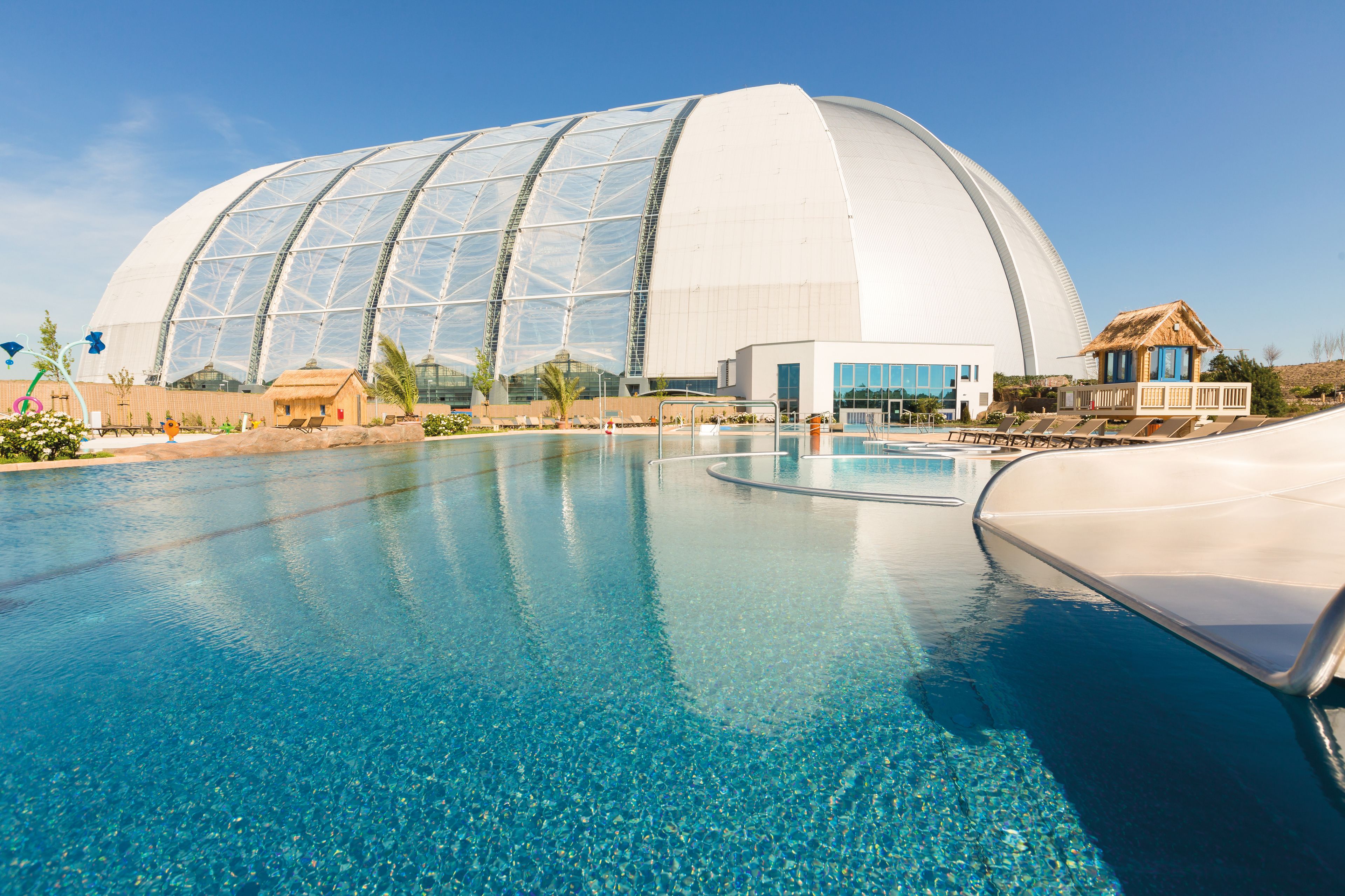 A large swimming pool with a modern dome-shaped building in the background.