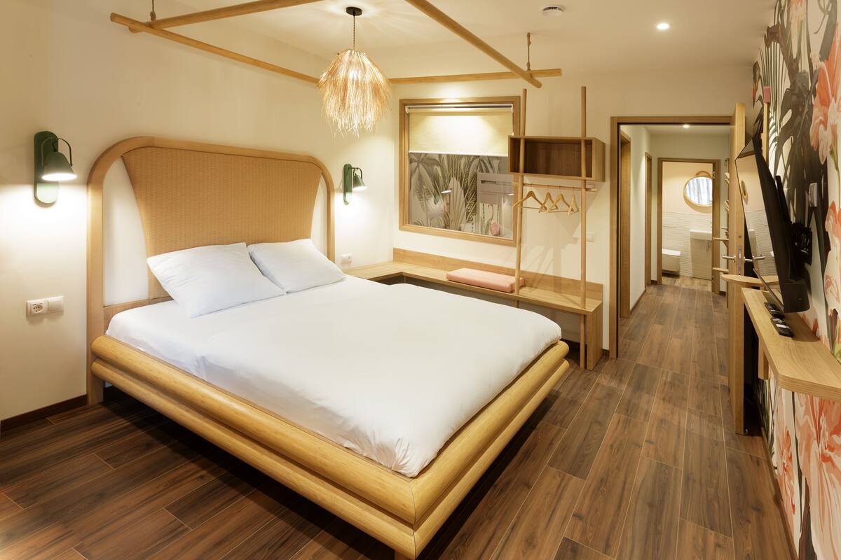 Une chambre à coucher moderne avec un cadre de lit en bois, une table de chevet, un luminaire suspendu et un grand miroir.