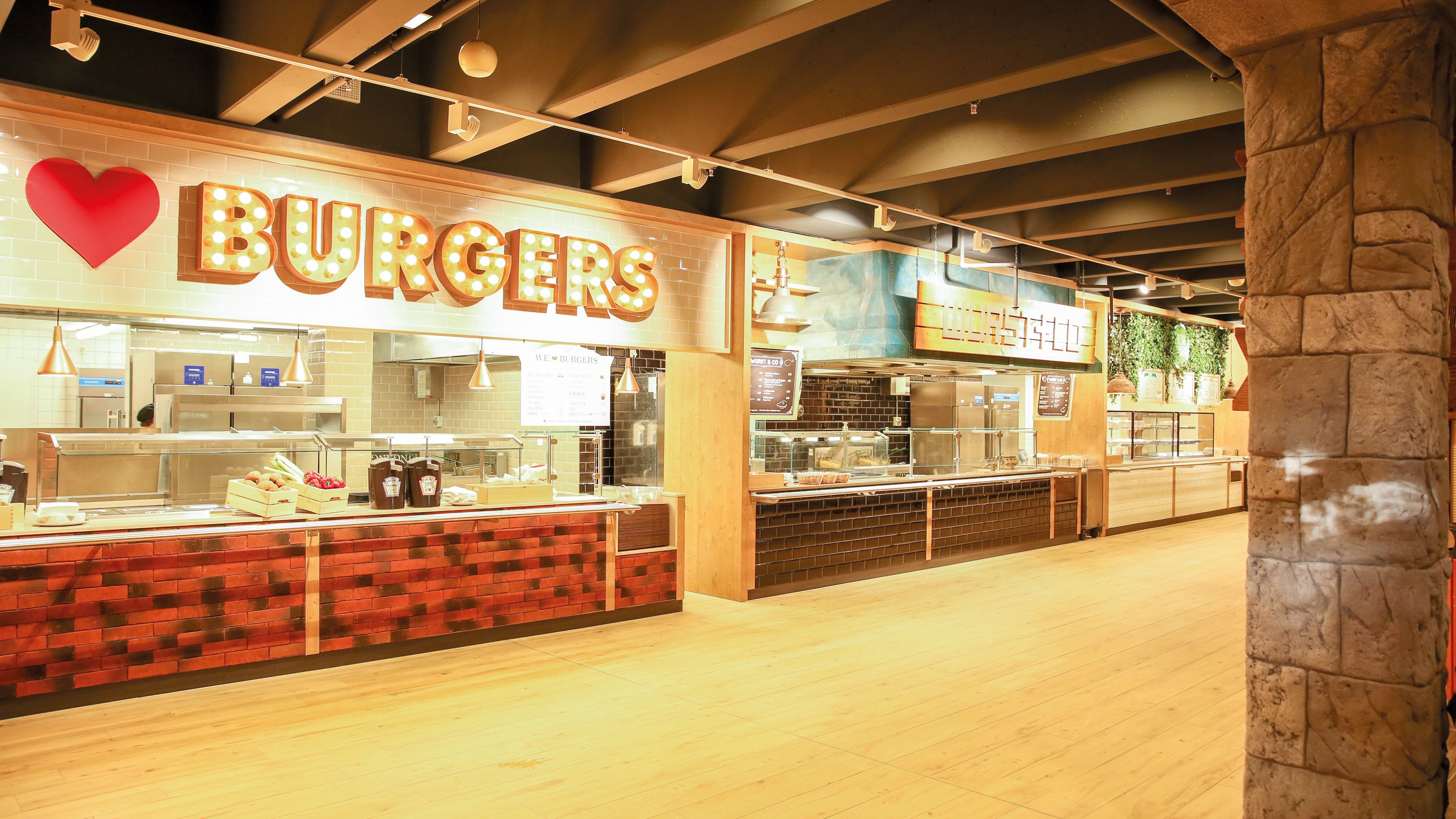 Un restaurant doté d’un comptoir en briques et d’une enseigne lumineuse indiquant qu’on y sert des hamburgers.