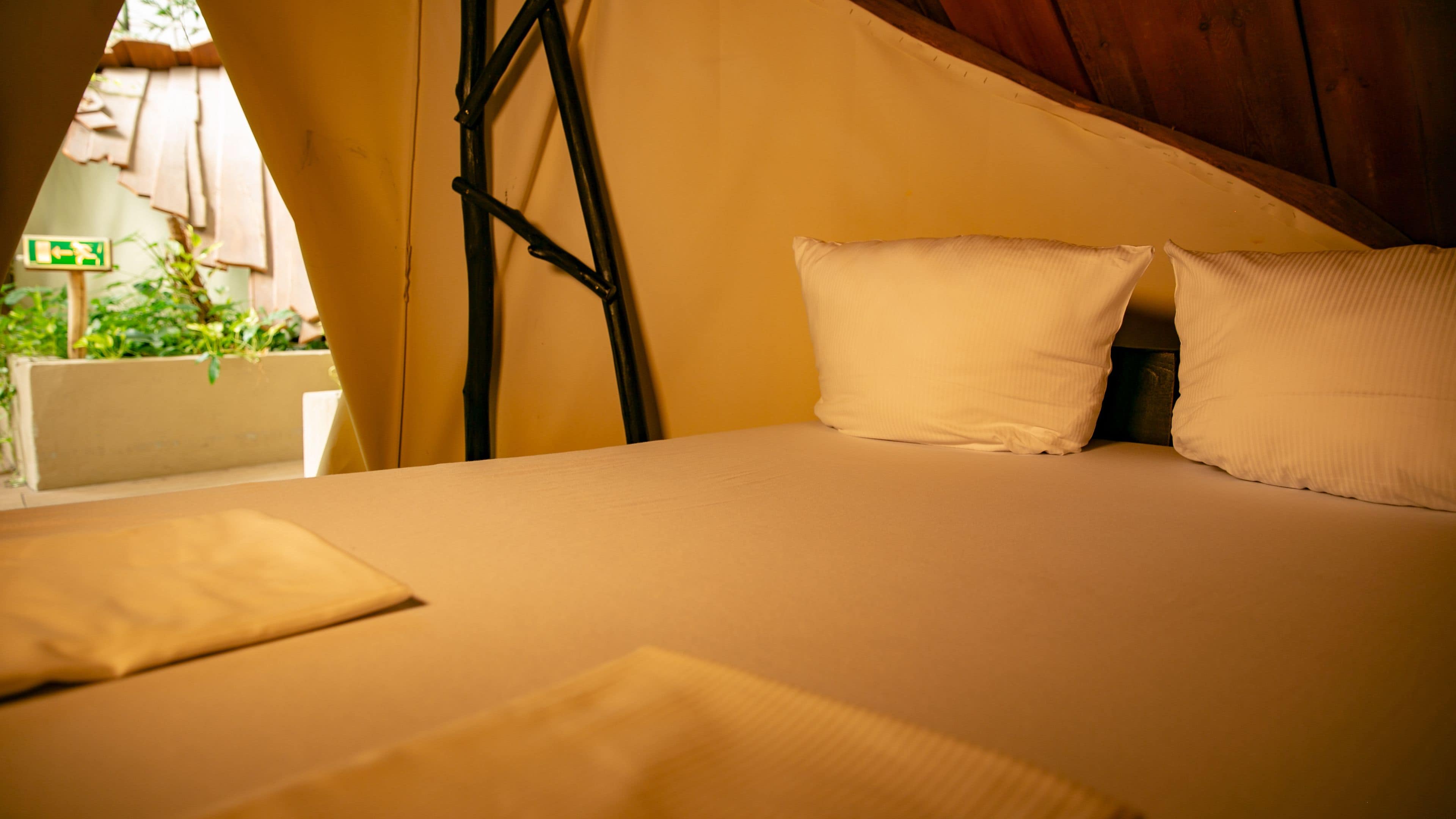 A bed with white pillows and a wooden ladder leaning against a wall.