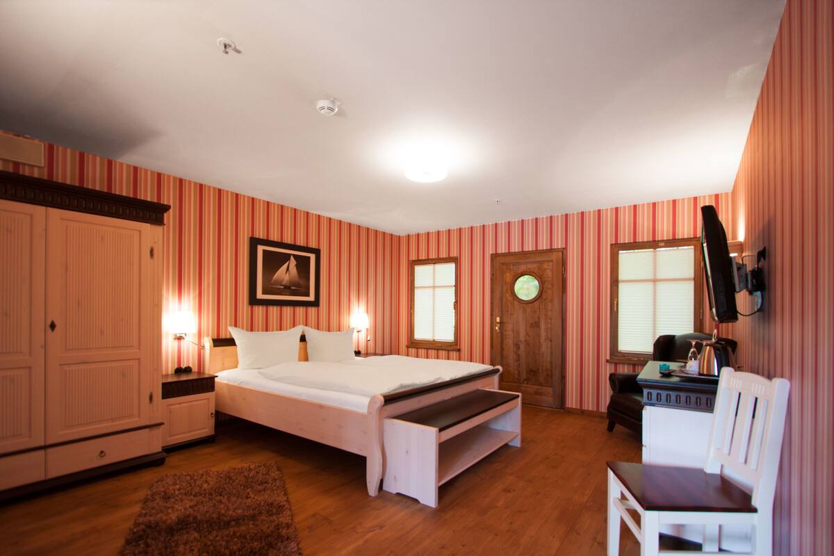Une chambre à coucher comprenant un lit, un bureau, une chaise, une armoire et une porte.