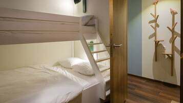 Una cama litera con escalera, una puerta de madera y un estante fijado a la pared con un adorno de pájaro.