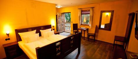 A bedroom with a wooden bed, bedside tables, a window with curtains, and a mirror on the wall.