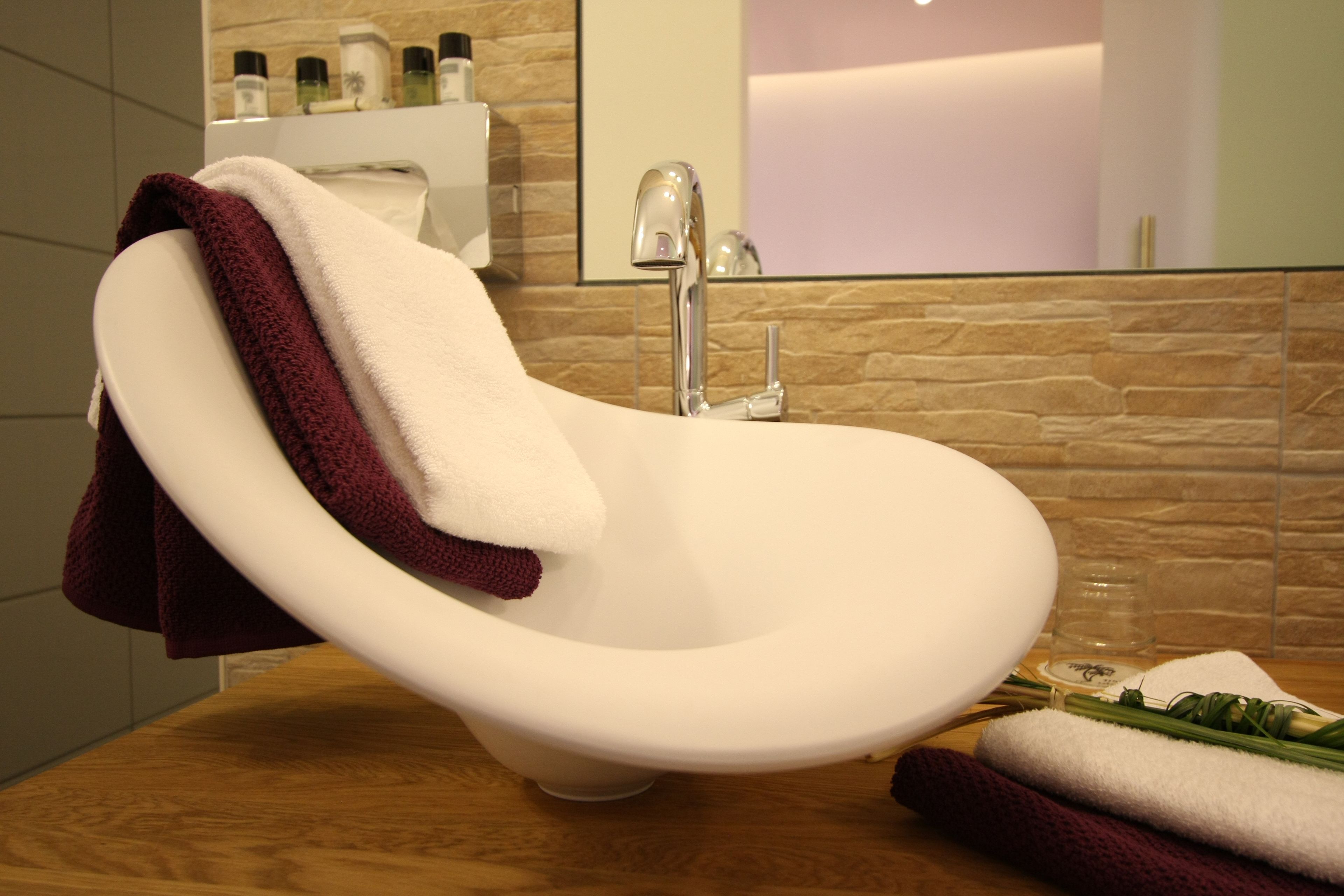 A modern bathroom with a freestanding bathtub, a wooden countertop, and a stone backsplash.