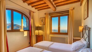 Une chambre avec deux lits, une fenêtre avec des rideaux, un radiateur et une lampe sur une table de chevet.