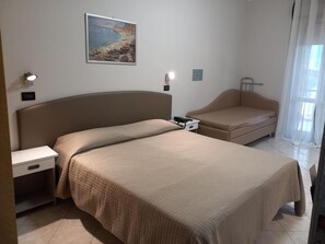 A bedroom with a bed, bedside table, lamp, and a painting on the wall. - Susy (Rimini)