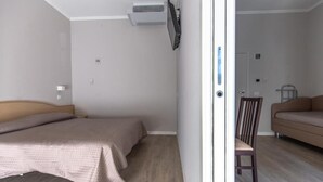 Ein Schlafzimmer mit Bett, Sessel, Sofa und Klimaanlage.