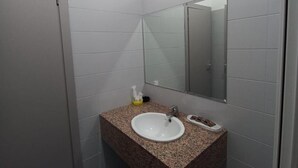 Ein kleines Badezimmer mit einem weißen Waschbecken, einer Granit-Arbeitsplatte und einem Spiegel darüber.