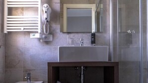Ein modernes Badezimmer mit integriertem Bidet, Waschbecken, Spiegel und Duschkabine.