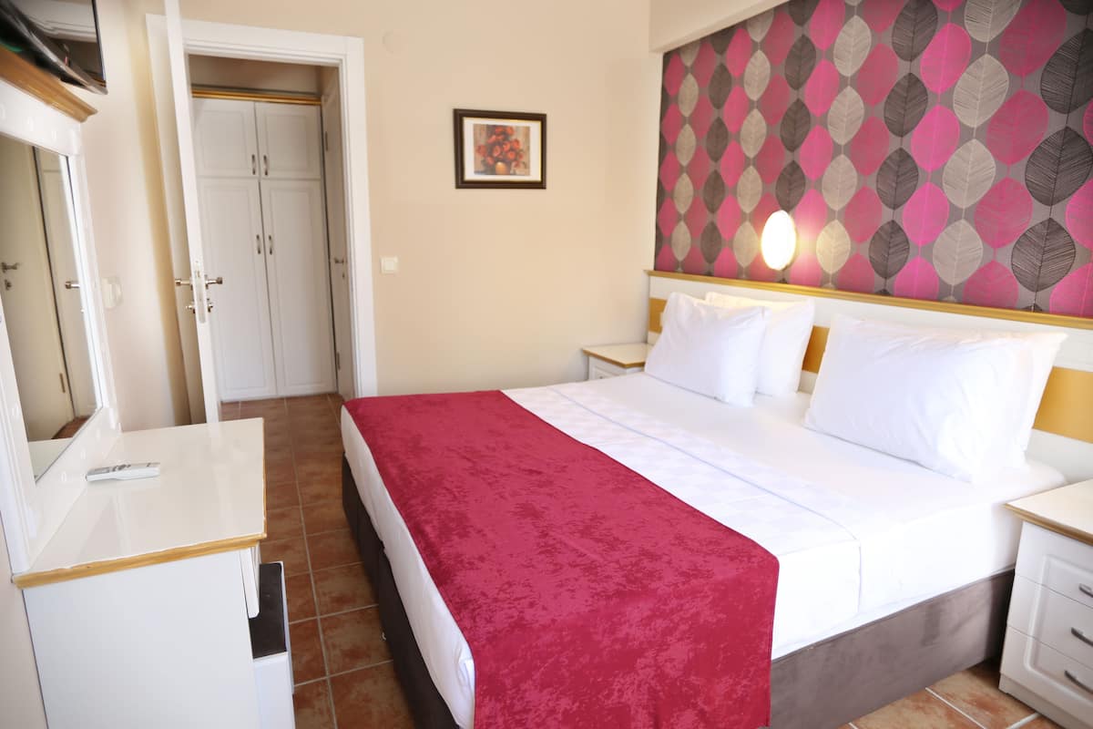 A hotel room with a bed, bedside tables, a wardrobe, and a wall with a patterned design.