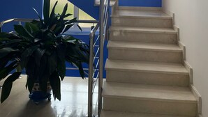 A staircase with a handrail, a potted plant, and a painting on the wall. - Hotel Villa de Llanes (Llanes)