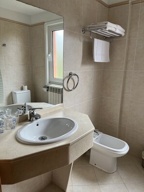 Une salle de bain moderne équipée d’un lavabo, de toilettes, d’un bidet et d’un porte-serviettes.