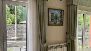 A room with a large sliding glass door, a radiator, and a painting on the wall. - Hotel Villa de Llanes (Llanes)