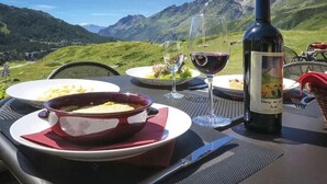 A dining table set outdoors with a bottle of wine, a bowl of food, and a glass of red wine. - Marmore (Cervinia)