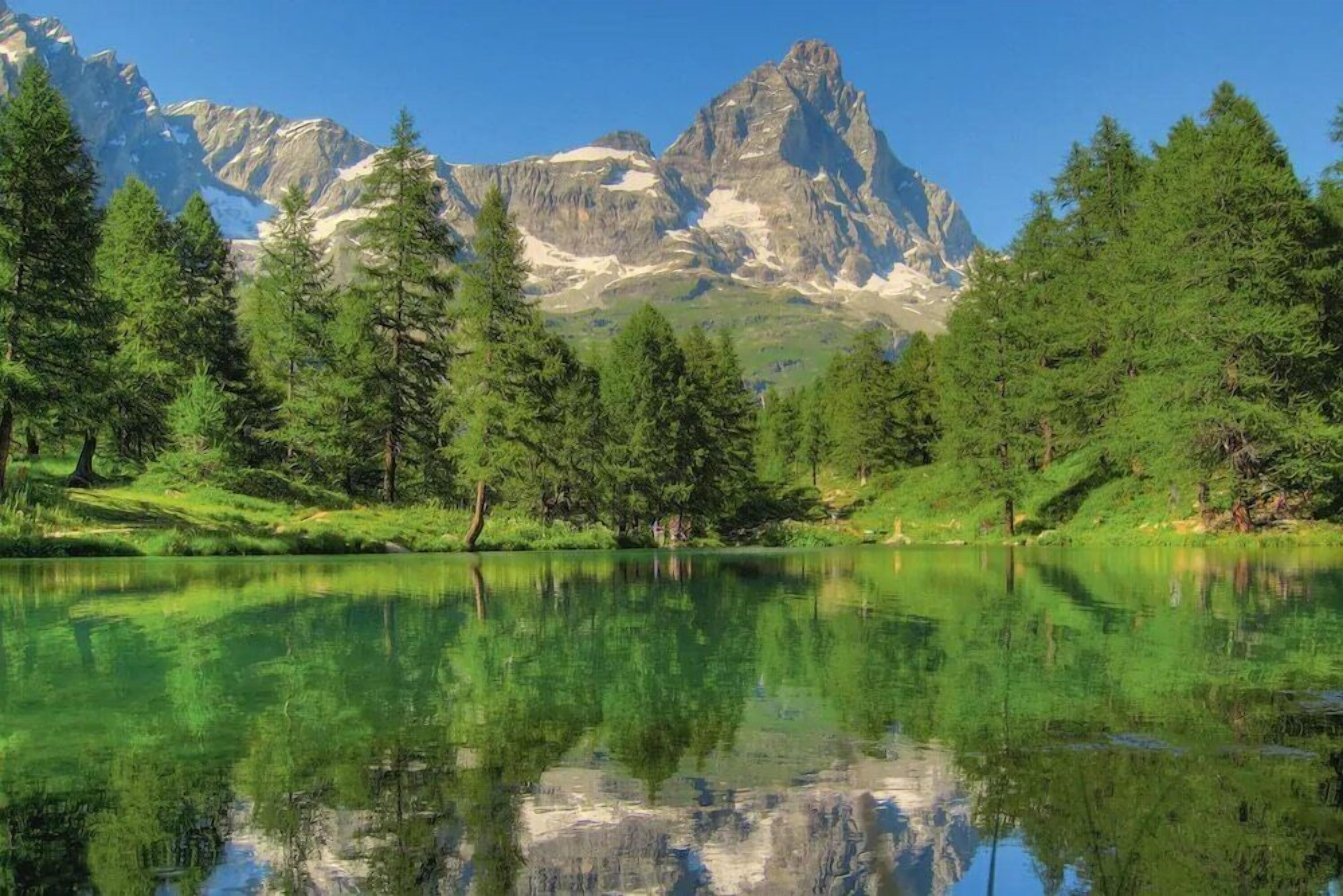 Un lago tranquillo con i riflessi di alberi e montagne sullo sfondo.