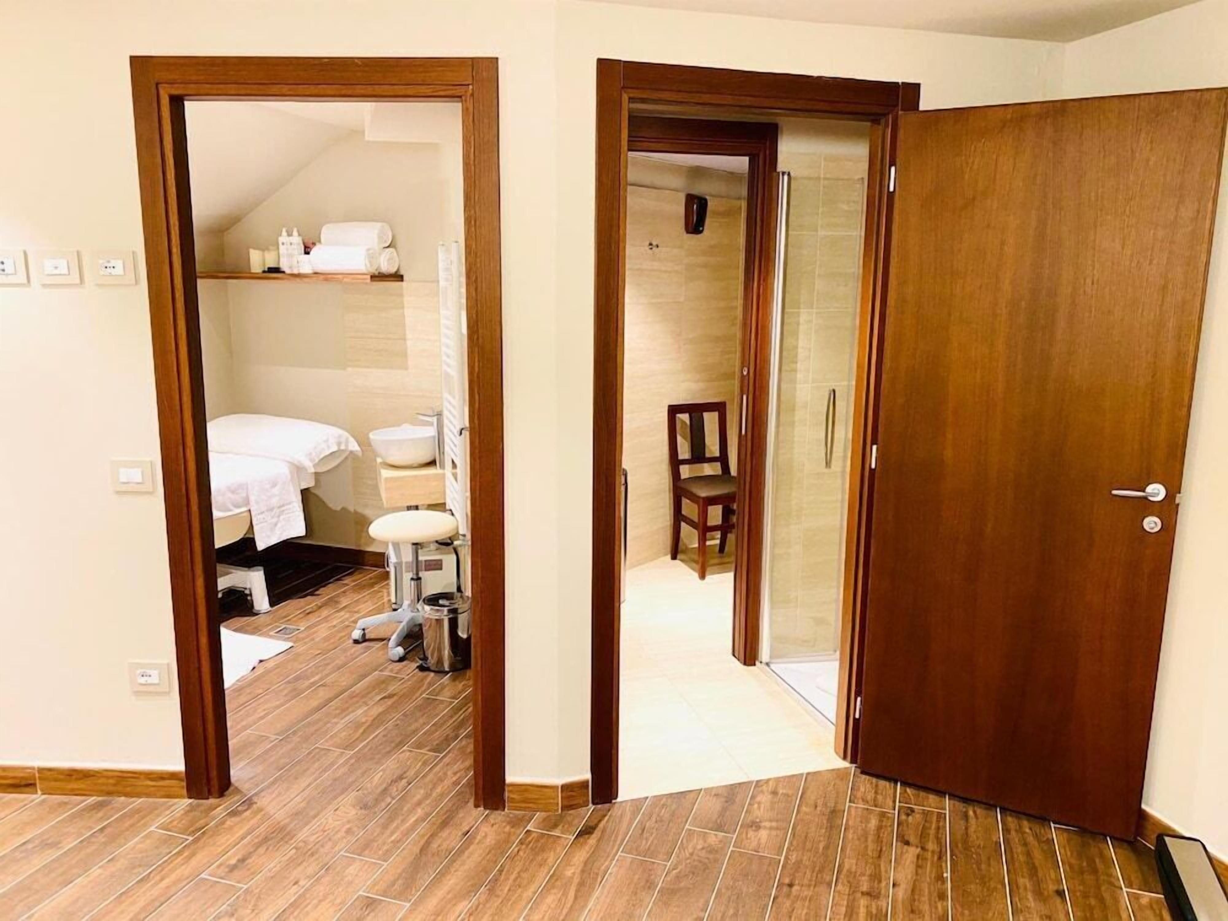 Ein Hotelzimmer mit Holzboden, einem Bett, einem Badezimmer mit Waschbecken und Toilette sowie einer Duschkabine.