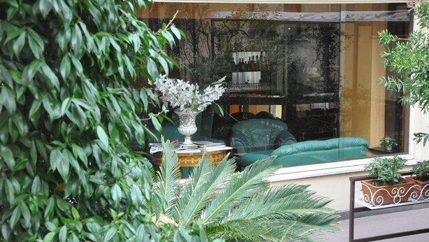 A cozy seating area with a green sofa and a decorative vase. - Hotel Mondial (Rapallo)