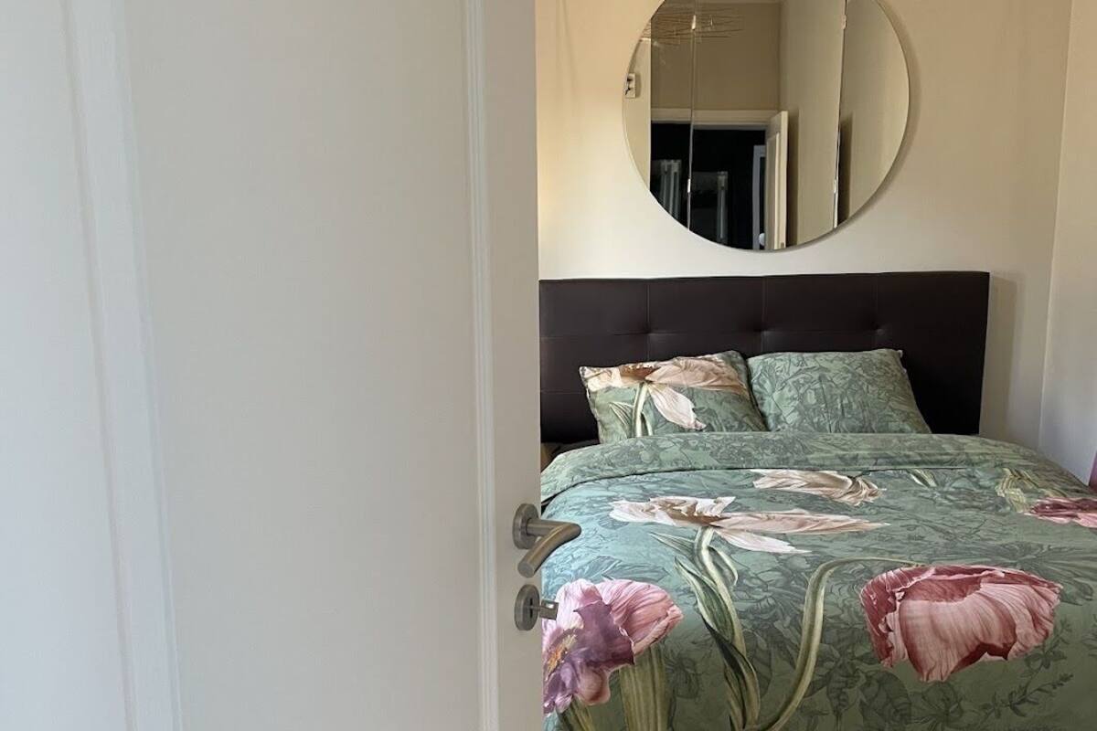 Une chambre à coucher avec un lit, un miroir rond et un luminaire moderne.