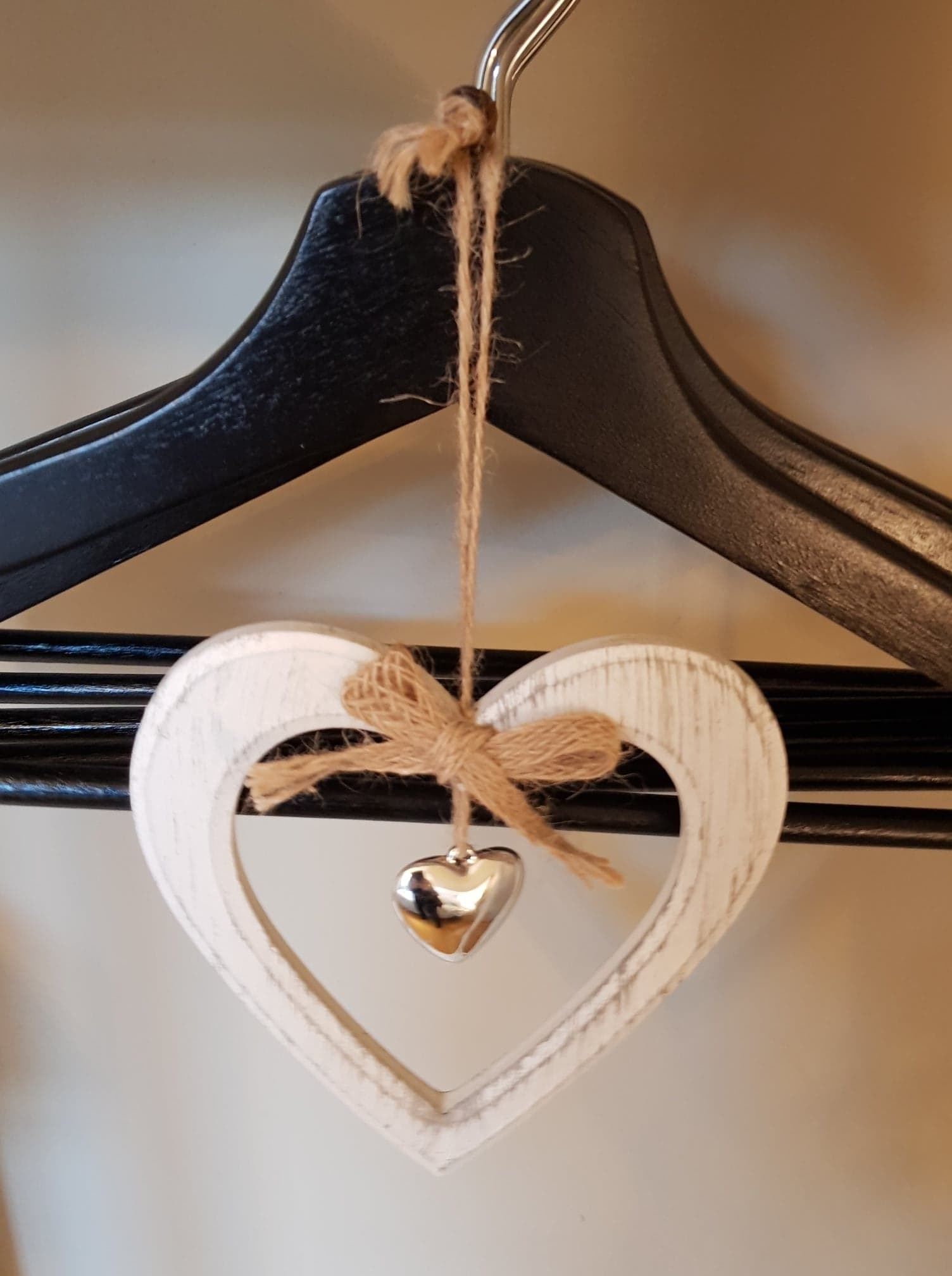 Un ornement en forme de cœur, avec un cœur métallique suspendu à un cintre noir.