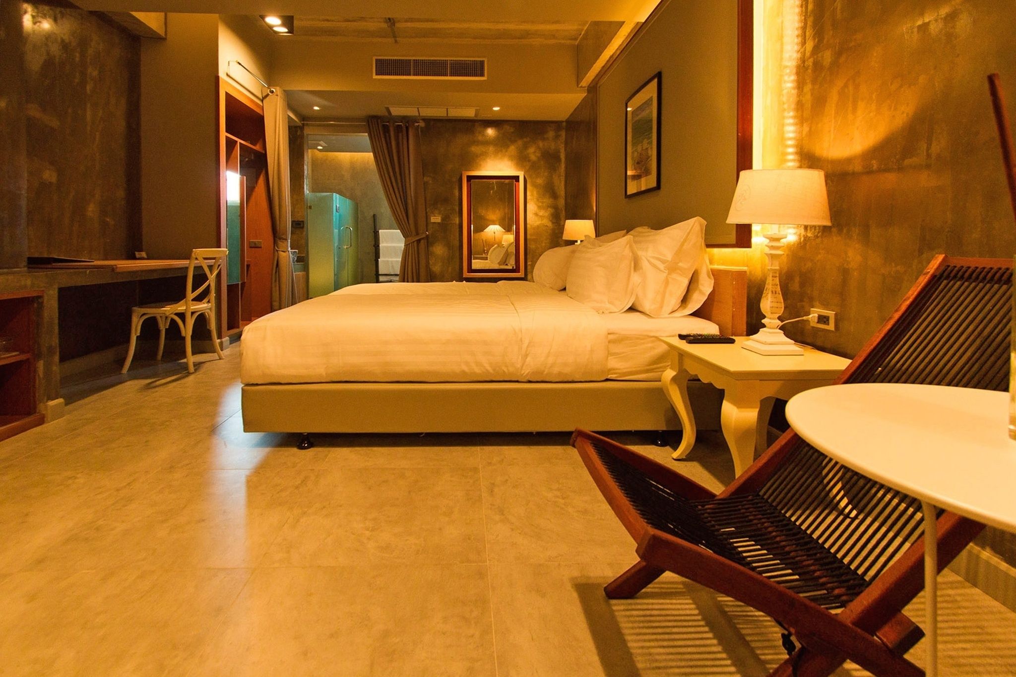 Ein Hotelzimmer mit einem großen Bett, einem Schreibtisch, einem Stuhl und einem kleinen Tisch.