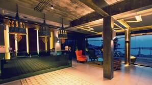 Een ruime lobby met een receptiebalie, een kamerbreed tapijt met patroon en hangende lampen.