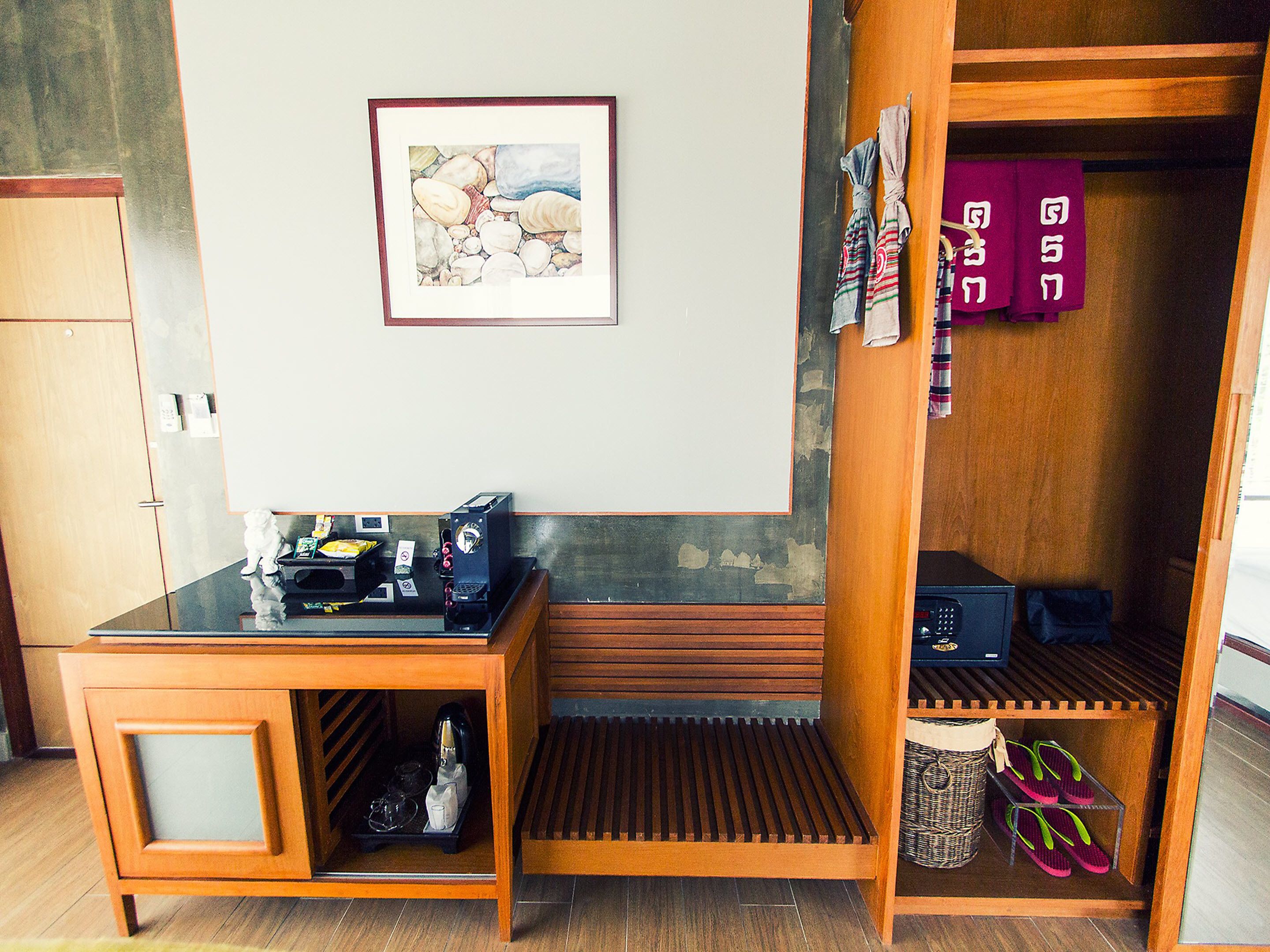 Habitación pequeña con escritorio de madera, cafetera y un estante con pantuflas.