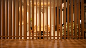 A room with a wooden floor, a dining table with chairs, and a view through a wooden partition. - Shizuoka Town Hotel (Shizuoka)