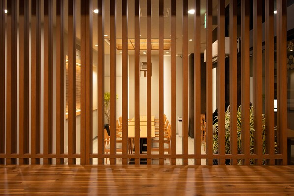 Una habitación con piso de madera, una mesa de comedor con sillas y vista a través de una partición de madera.