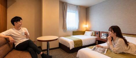 Una habitación de hotel con una cama, una pequeña mesa redonda y un sofá.